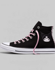 A black high-top sneaker inspired by the Converse All Star design, featuring pink laces, a white rubber toe cap and midsole, and a Kuromi character patch on the side. The shoe is photographed from a side profile against a solid light gray background.