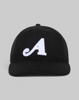 A black baseball cap with a white embroidered script letter 'A' on the front, photographed against a solid light gray background.