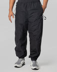 Black lightweight jogger-style pants with an elastic waistband and drawstring details, shown on a model from the waist down against a light gray studio background.