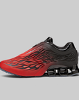 A red and black athletic sneaker with a flame-like pattern on the upper, black laces, and a prominent black cushioning system on the sole, shown against a solid gray background.