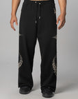 Black wide-leg sweatpants with silver rhinestone star patterns on the lower legs, modeled on a person against a gray studio background.