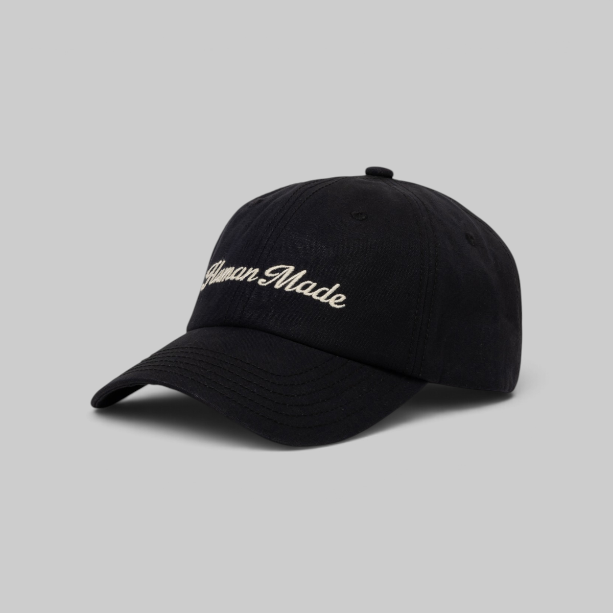A black baseball cap with a white embroidered Wilson logo on the front, set against a solid light beige background.