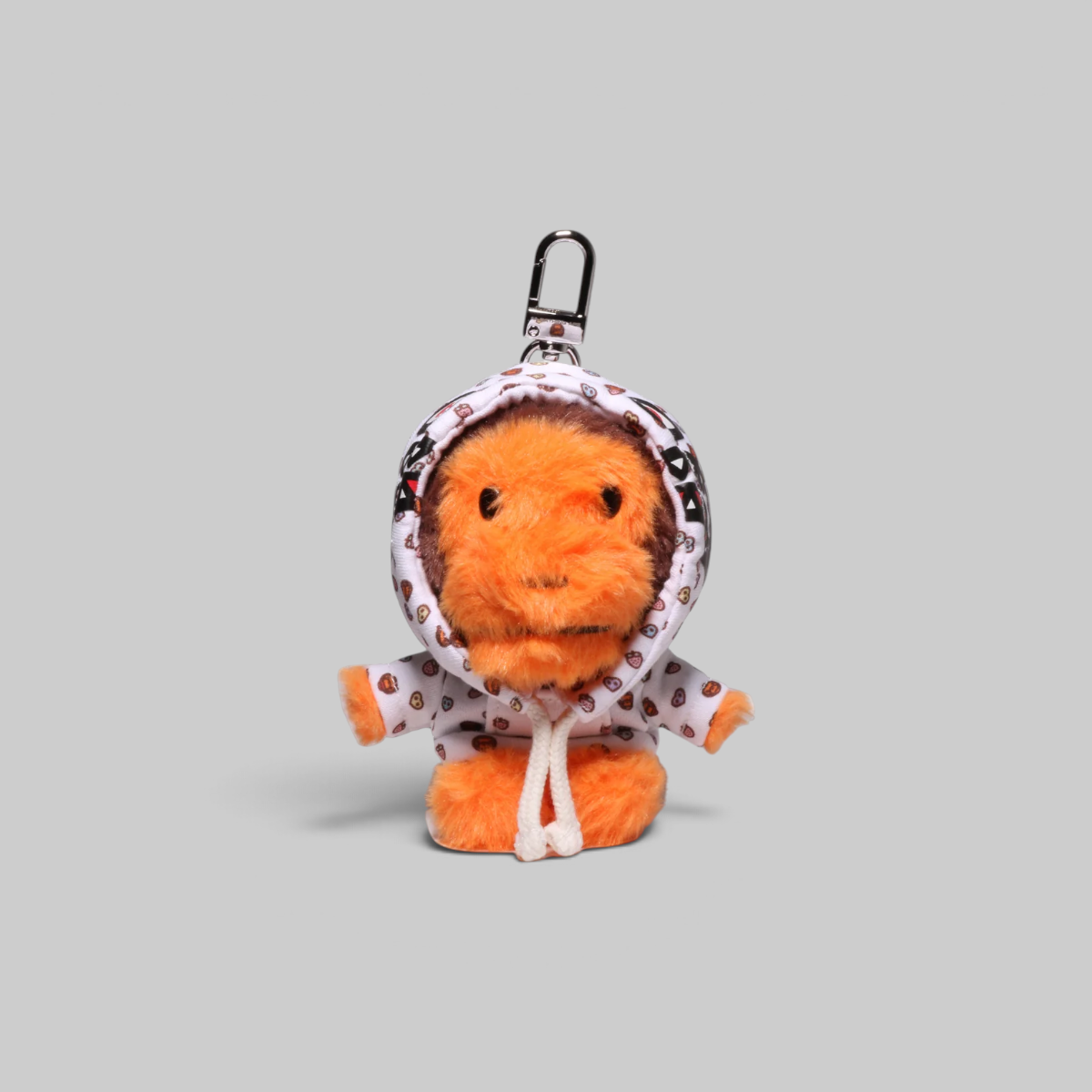 An orange plush monkey keychain wearing a white hooded raincoat with small red and black polka dots, attached to a black metal clasp, shown on a solid gray background.