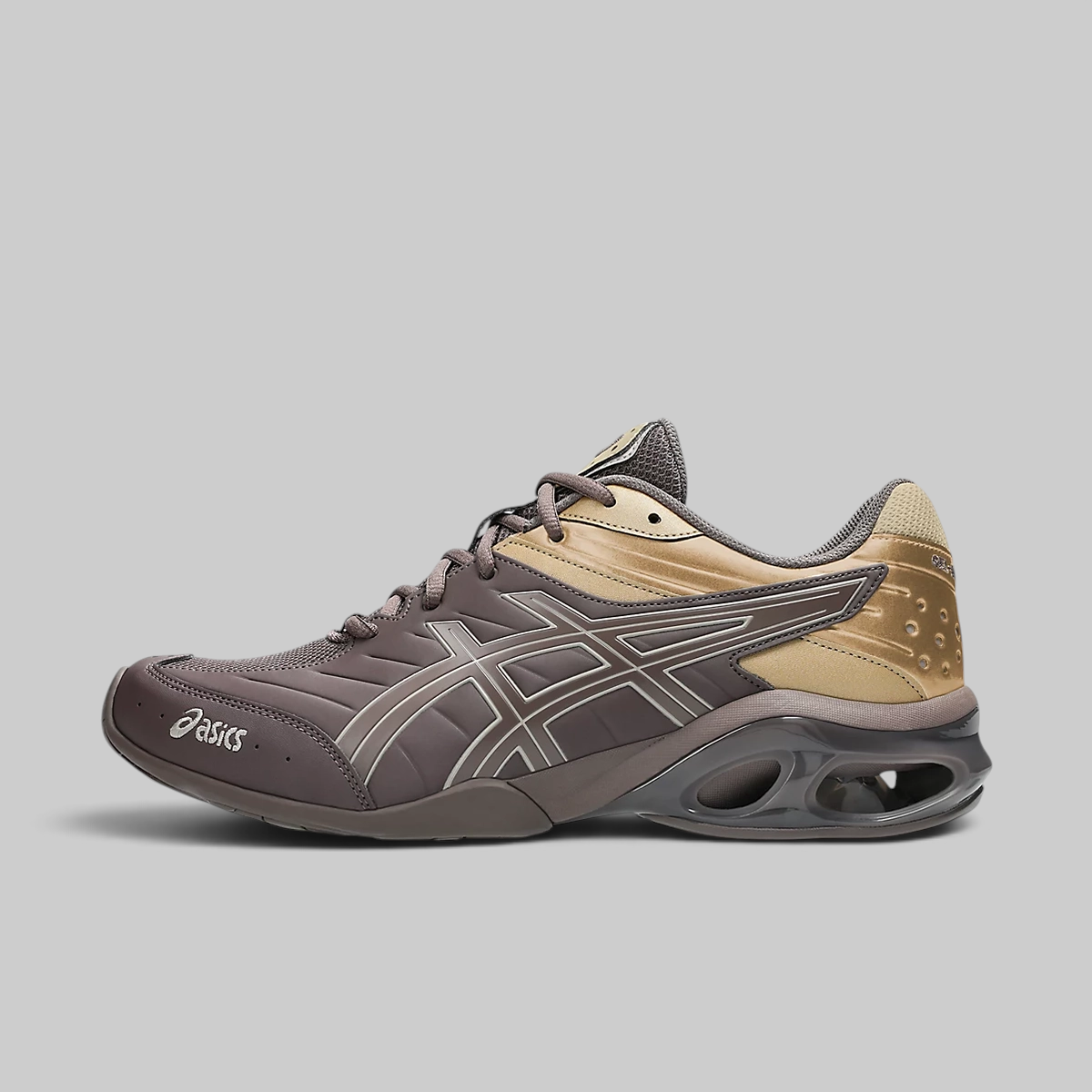 An ASICS sneaker in dark brown and tan, featuring the brand's signature side stripe design and a dark gray cushioned sole, shown against a solid gray background.