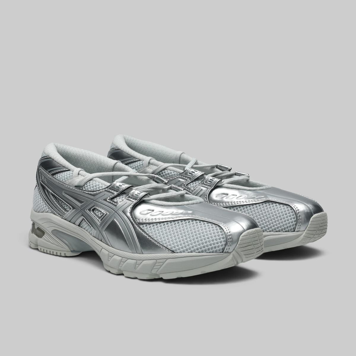 A pair of ASICS Gel-Kayano running shoes in metallic silver and light gray, shown from a three-quarters angle on a solid gray background.