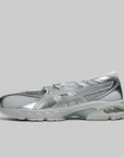 A metallic silver athletic sneaker with mesh panels and a chunky sole, shown in profile against a solid gray background.