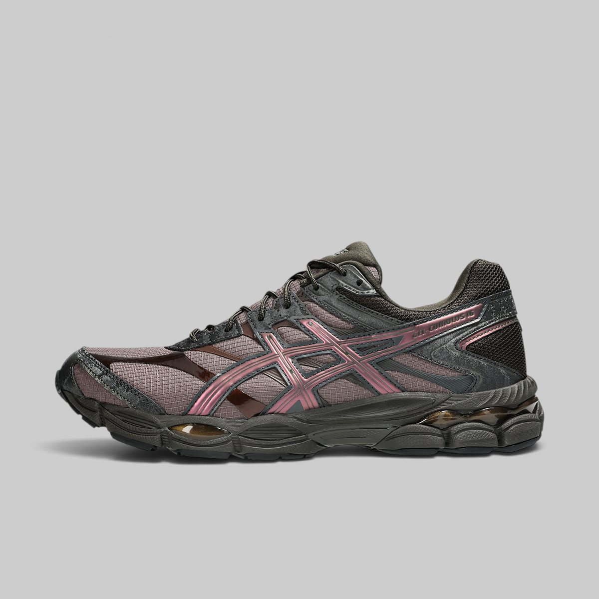 A single ASICS running shoe in a dark charcoal gray and black mesh with metallic rose gold overlays, shown in a side profile on a solid gray background.