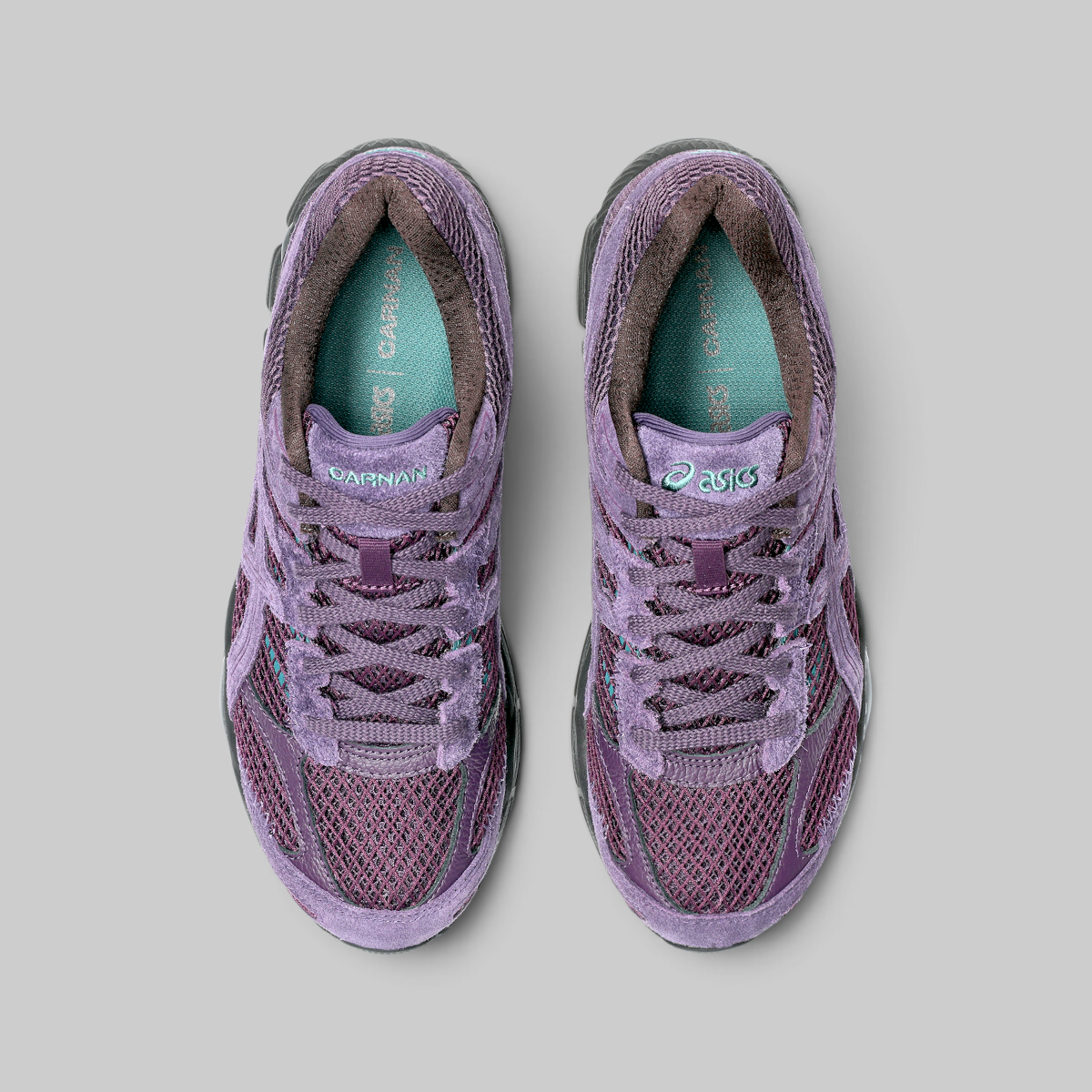 A pair of Asics running shoes in a dusty purple colorway, shown from a top-down view on a neutral gray background.