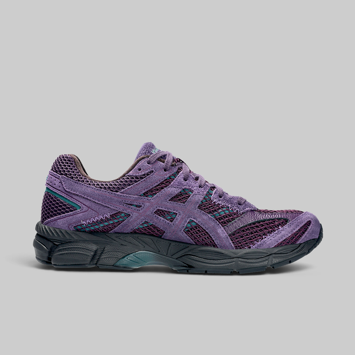 A single running shoe in purple suede and mesh with dark gray and teal accents, shown in a side profile on a solid gray background.