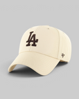 A cream-colored baseball cap featuring a black embroidered 'LA' logo on the front and a black '47' brand logo on the side, set against a solid gray background.