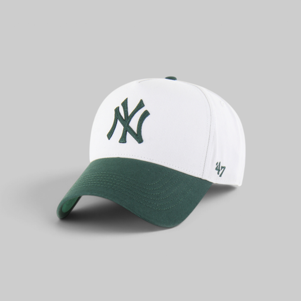 A white and dark green baseball cap featuring the New York Yankees interlocking logo on the front and a '47' brand logo on the side, set against a solid gray background.