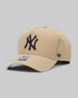 A beige New York Yankees baseball cap by '47, featuring an embroidered navy blue NY logo on the front and a '47 logo on the side, set against a solid gray background.