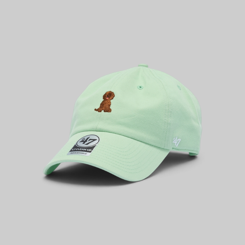 A mint green baseball cap by '47 featuring an embroidered brown dog on the front and a '47 logo on the side, set against a solid gray background.