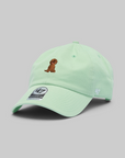 A mint green baseball cap by '47 featuring an embroidered brown dog on the front and a '47 logo on the side, set against a solid gray background.