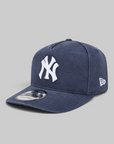A navy blue New York Yankees fitted cap with a white embroidered NY logo on the front and a white New Era flag logo on the side, shown on a neutral gray background.