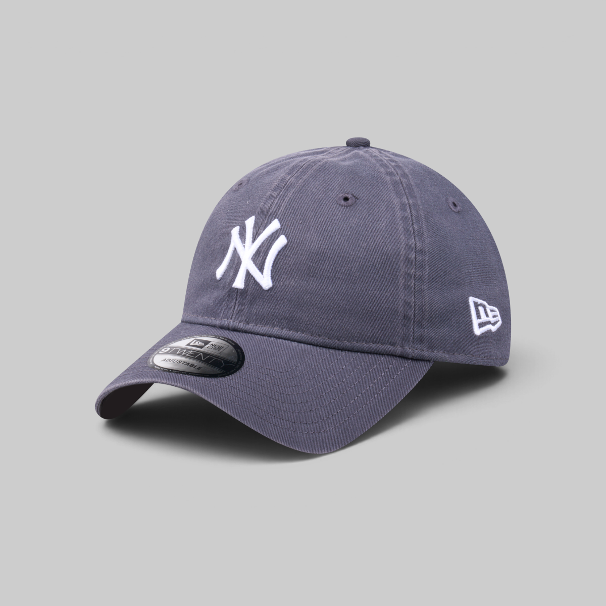 A dark slate blue New York Yankees baseball cap with a white embroidered NY logo on the front and a white New Era flag logo on the side, shown on a neutral gray background.