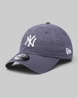 A dark slate blue New York Yankees baseball cap with a white embroidered NY logo on the front and a white New Era flag logo on the side, shown on a neutral gray background.