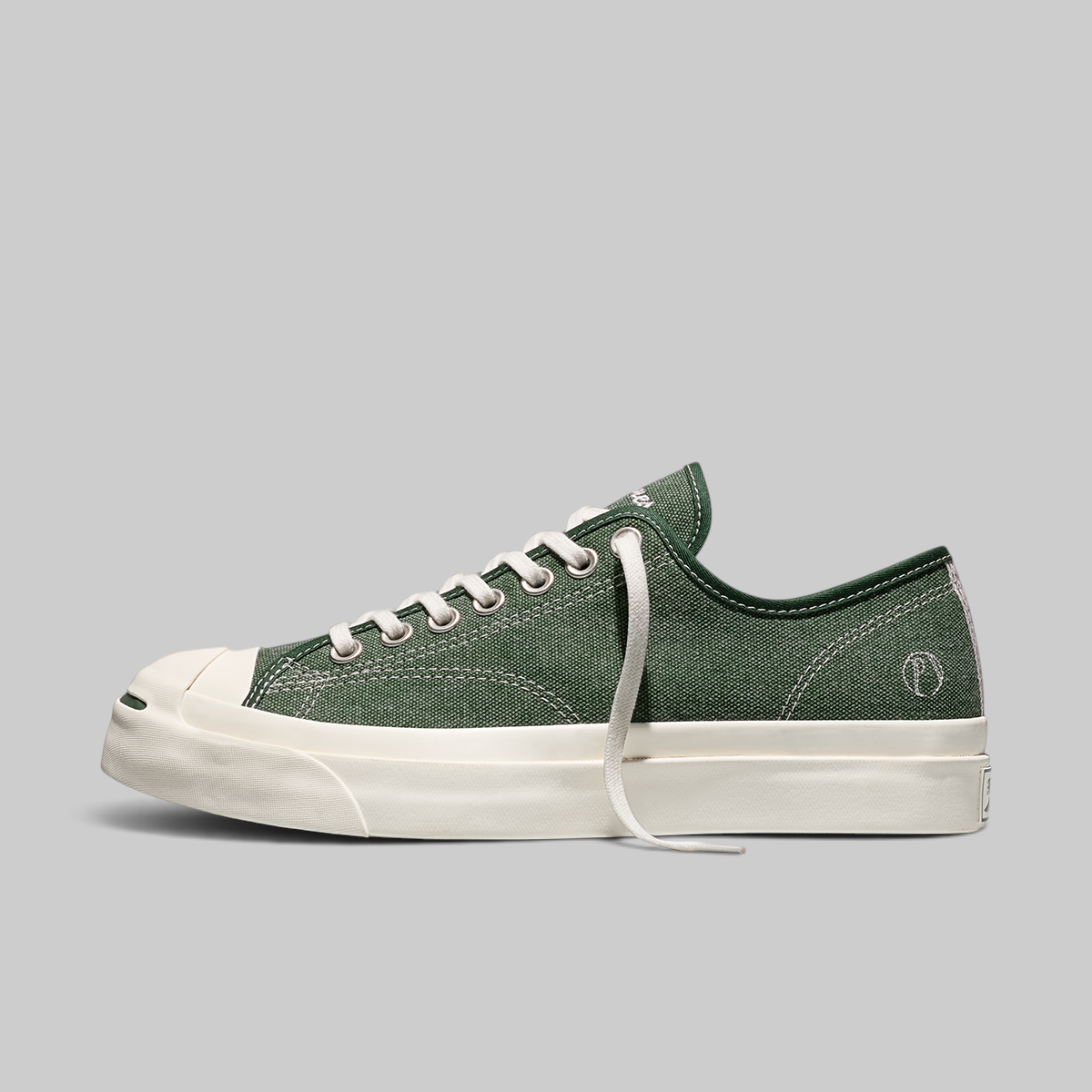 Green sneaker with white sole on a light gray background