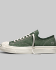 Green sneaker with white sole on a light gray background