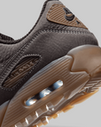 Close-up of a Nike Air Max sneaker in dark gray suede with a translucent brown Air Max sole and heel cushioning