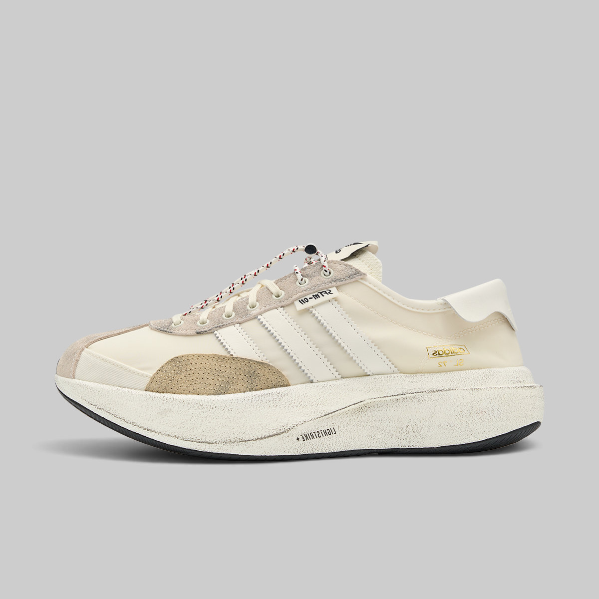 A low-top sneaker in cream and beige suede and mesh, featuring three white stripes on the side, a textured beige heel counter, a white rubber heel tab, and a chunky off-white platform sole with a black outsole.