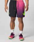 A model from the waist down wearing Nike athletic shorts with a split black and pink-to-purple design, neon green swoosh and drawstring tips, white socks, and matching pink and green sneakers against a light gray studio background.