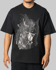 A man wearing a black oversized t-shirt with a large white and gray graphic print of a snarling dog on the front, set against a solid gray background.