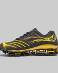 A black and yellow athletic sneaker with a textured upper, yellow lightning bolt graphics, and a distinctive yellow and black cushioned sole, shown against a solid gray background.