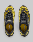 A pair of Adidas Originals Superstars sneakers shown from a top-down view, featuring a black and yellow colorway with a yellow lightning-bolt pattern on a gray background.