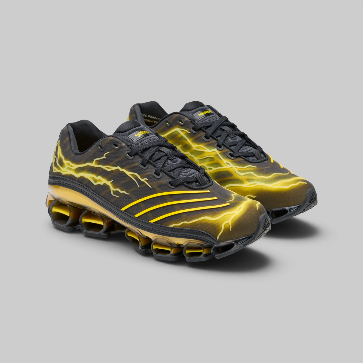 A pair of Nike Air Max 90s sneakers in black with vibrant yellow lightning-bolt graphics and a gold-toned cushioned sole, displayed on a neutral gray background.