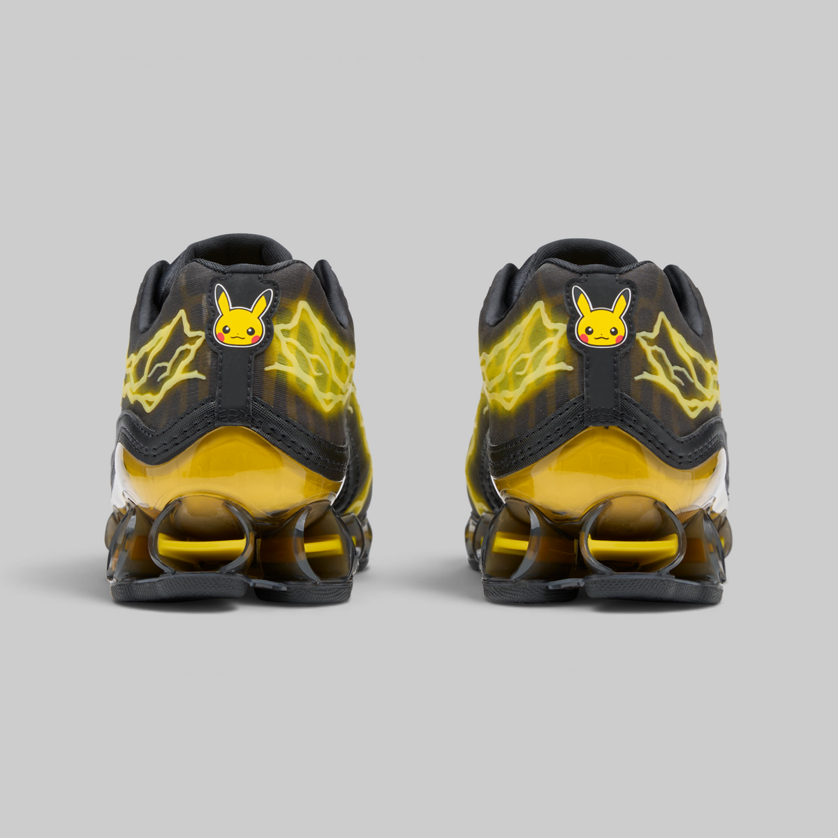 A pair of Nike Air Max 90 sneakers in a black and yellow Pikachu theme, shown from the back against a solid gray background.