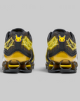 A pair of Nike Air Max 90 sneakers in a black and yellow Pikachu theme, shown from the back against a solid gray background.