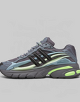 A single Adidas sneaker shown in profile against a solid light gray background. The shoe features a dark gray and black upper with light blue overlays, a pale yellow-green midsole accent, and a bright neon green outsole.