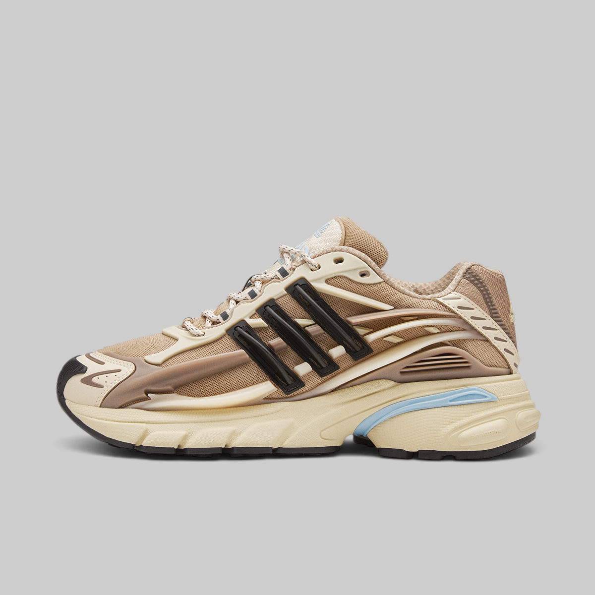 Adidas Pharrell Williams Adistar Jellyfish - "Crystal Sand" sneaker in beige and brown with black three-stripes and a light blue accent on the midsole, shown in a side profile on a solid gray background.