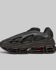 A black Nike sneaker with a distinctive hollow, bubble-like upper and a translucent dark red midsole cushioning system, shown in a side profile on a light gray background.