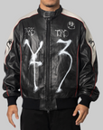 Y-3 x Chito black leather bomber jacket with white graffiti-style graphics, red piping, and beige shoulder panels, photographed against a solid gray background.