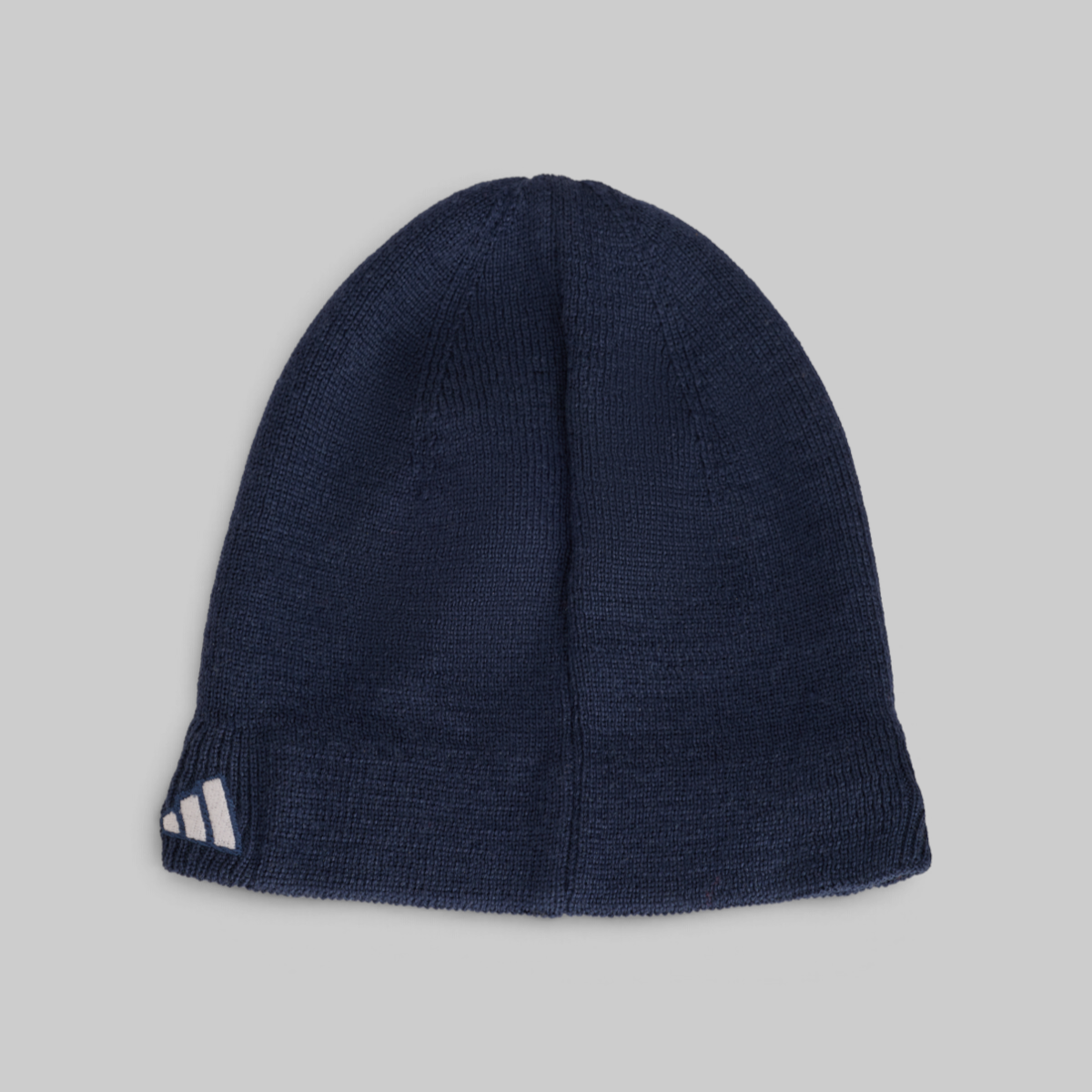 A navy blue ribbed knit beanie hat with a white Adidas logo on the folded cuff, shown against a solid light gray background.