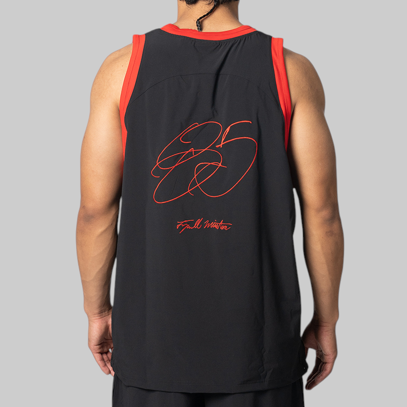 A man shown from the back wearing a black athletic tank top with red trim and a large red signature graphic on the back, photographed against a plain light gray studio background.