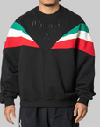 A man wearing a black crewneck sweatshirt with green, white, and red color-blocked shoulder stripes and embossed 'Chavarria' lettering on the chest, photographed against a solid gray background.