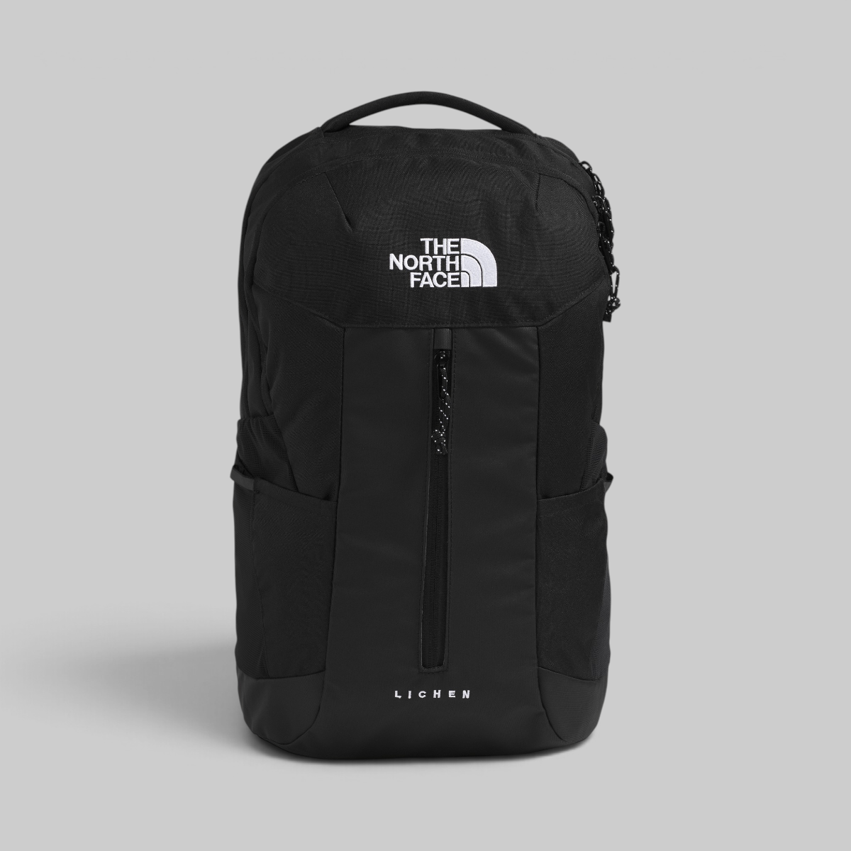 The North Face Lichen backpack in black, featuring a white printed logo on the front and a vertical zippered pocket, set against a solid gray background.