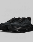 A pair of black athletic sneakers with a textured knit upper and thick cushioned soles, photographed on a light gray background.