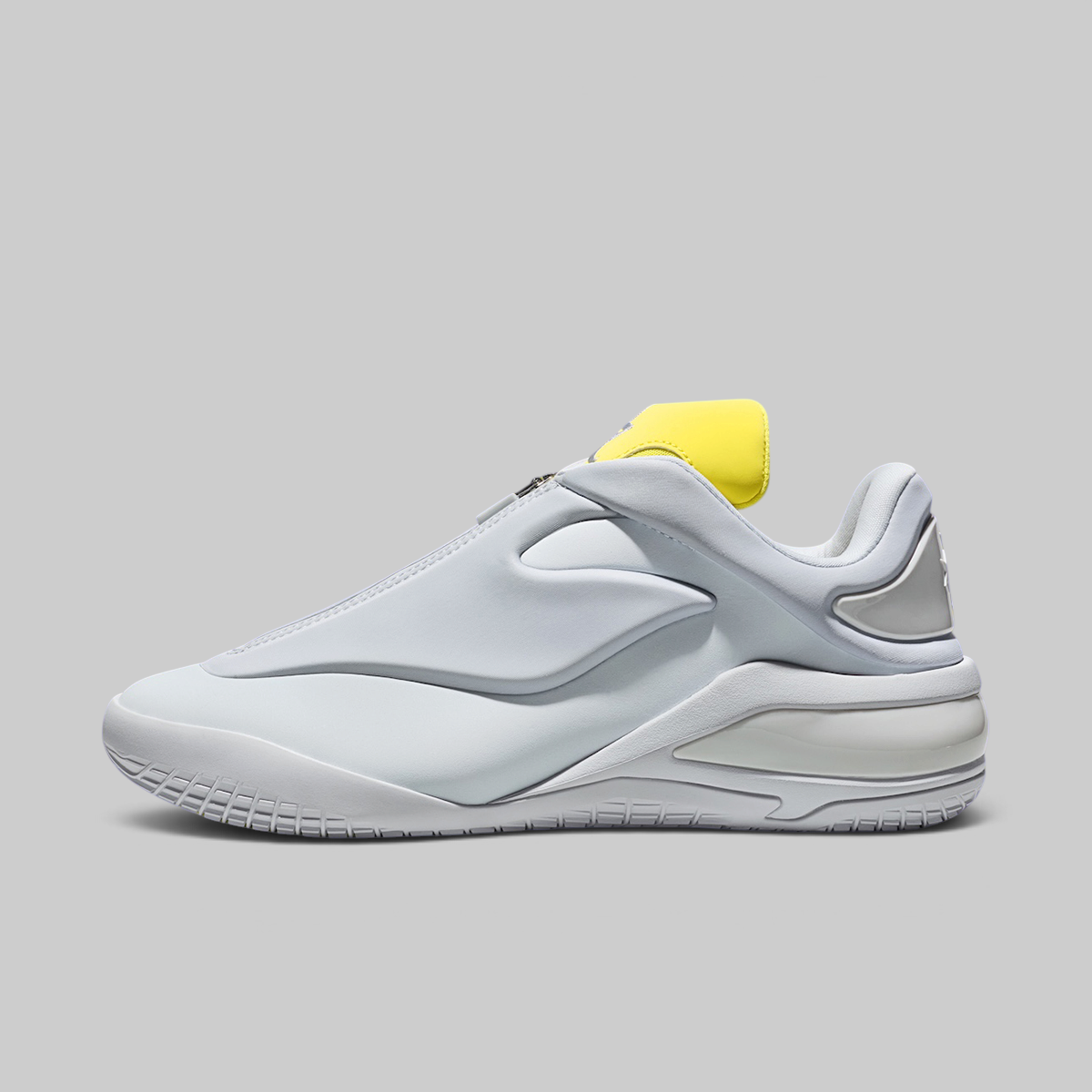 A white and light gray athletic sneaker with a bright yellow heel tab, shown in a side profile on a solid gray background.