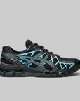 A black ASICS Gel-Kayano running shoe with bright light blue accents and white branding stripes, shown from a side profile on a solid gray background.