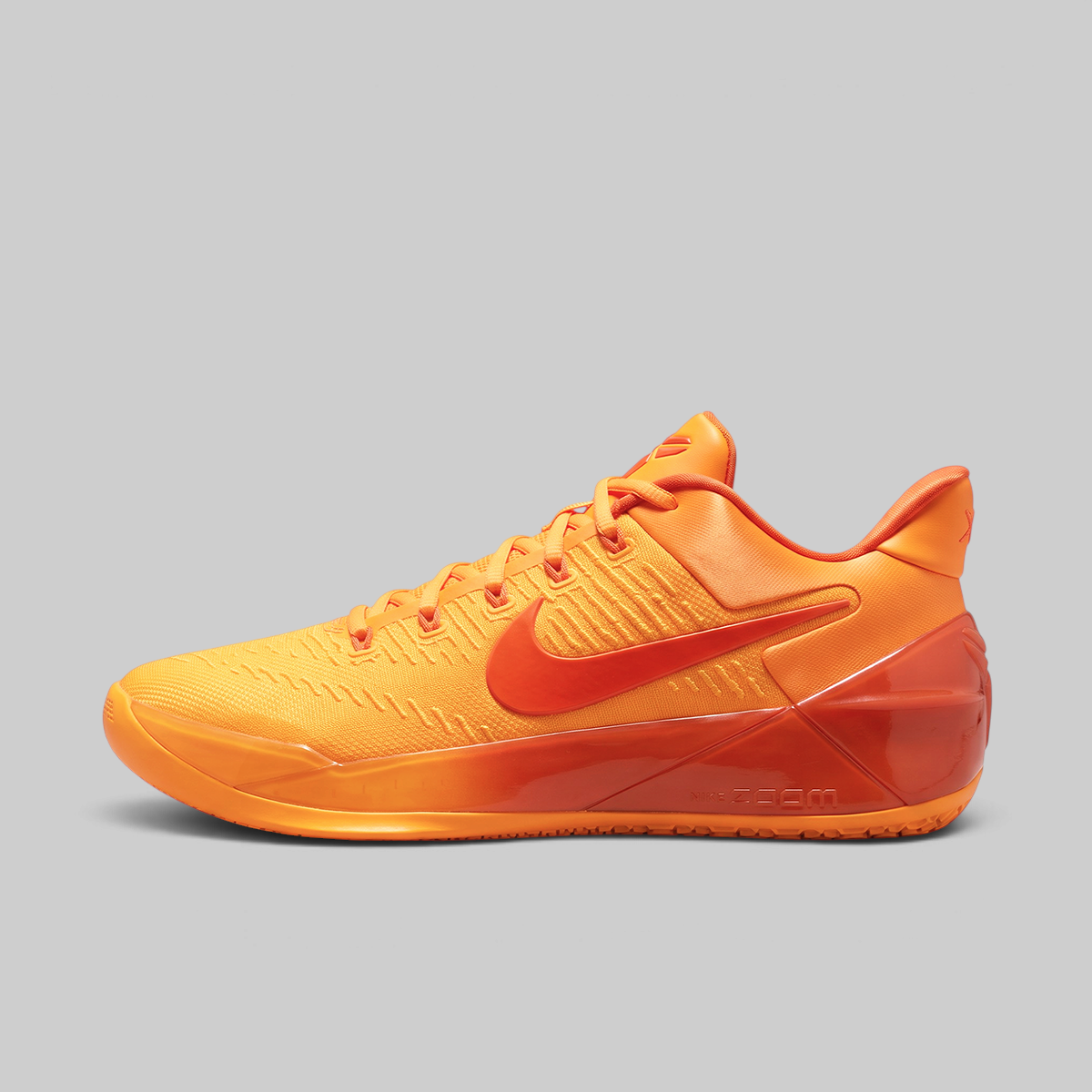 A Nike basketball shoe in a vibrant orange-to-red gradient, shown from the side against a solid gray background.