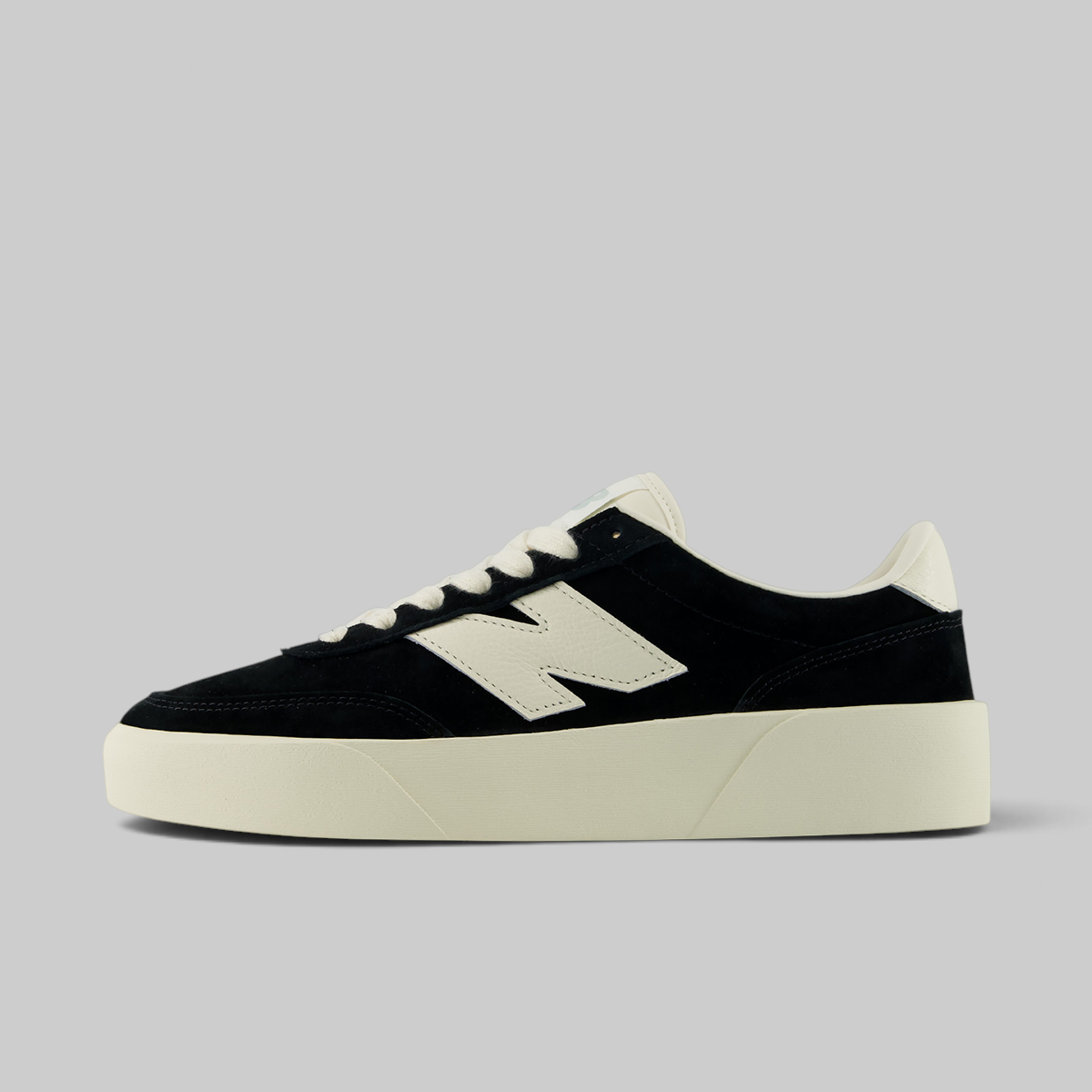 A low-top sneaker in black suede and off-white leather, featuring a thick off-white platform sole and a large 'N' logo on the side, photographed against a solid light gray background.